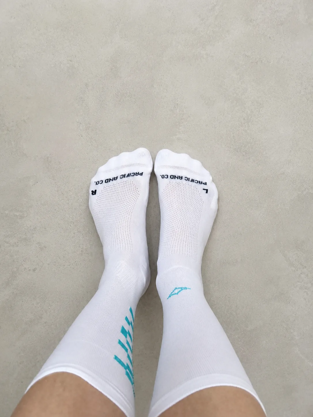 Calcetines Pacific & Co. HYPER PRO 1.0 WT blancos con detalles turquesa, vistos desde arriba, con el texto Pacific and Co. y las letras L y R en la puntera