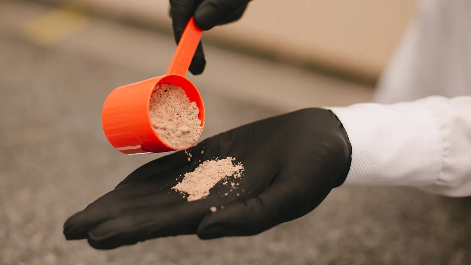 Cazo dosificador vertiendo creatina en polvo sobre una mano