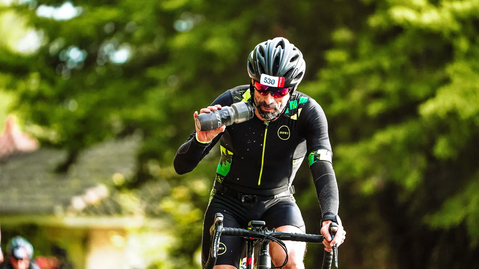 Ciclista con casco bebiendo de su bidón durante una marcha