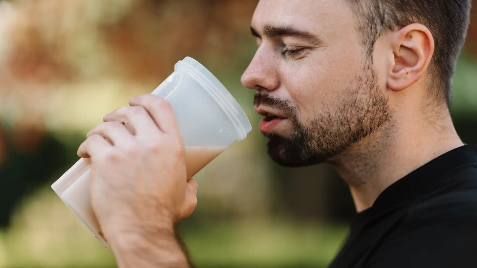 Deportista bebiendo un batido de proteínas al aire libre tras entrenar