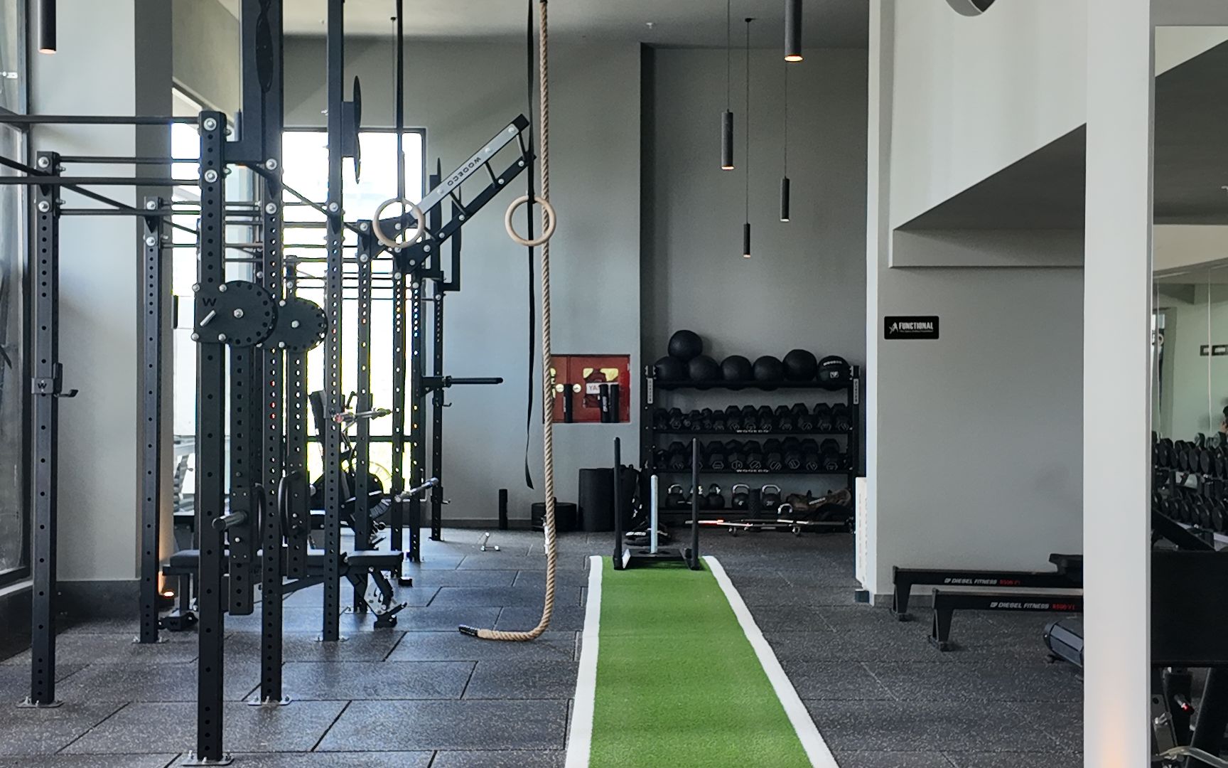 Gimnasio funcional con pista de trineo (sled track) verde, rack de pesas y cuerdas — el tipo de entorno donde se celebran las pruebas de Hyatlón