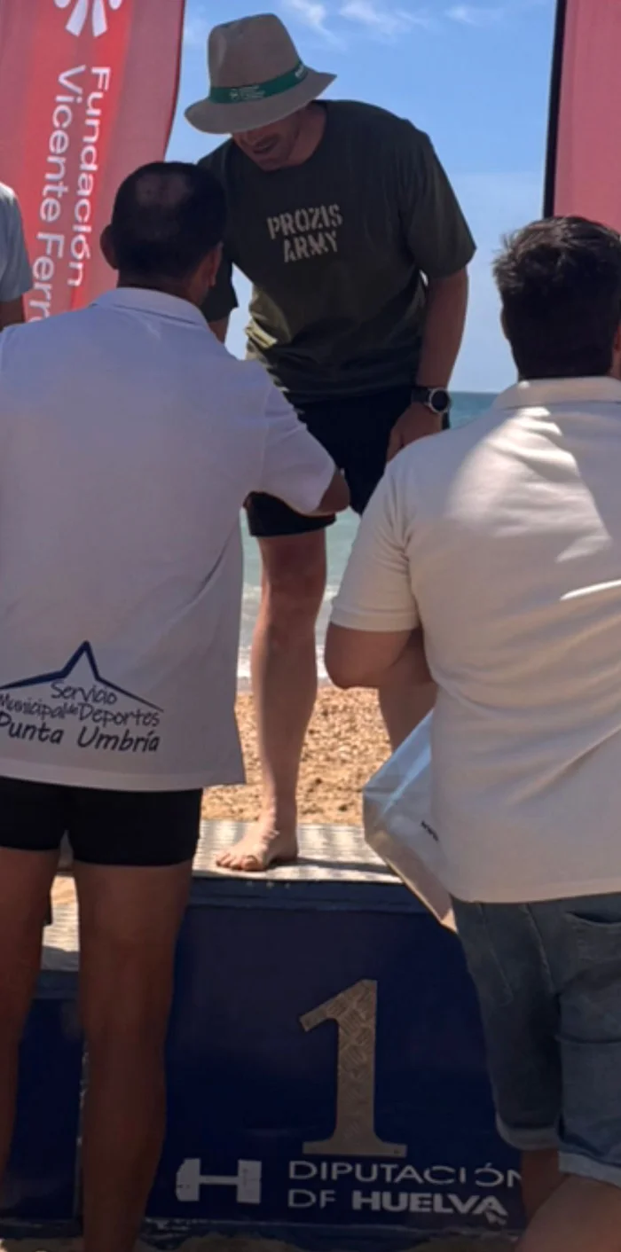 Abraham en lo alto del podio de la travesía a nado de Punta Umbría, con camiseta de Prozis Army