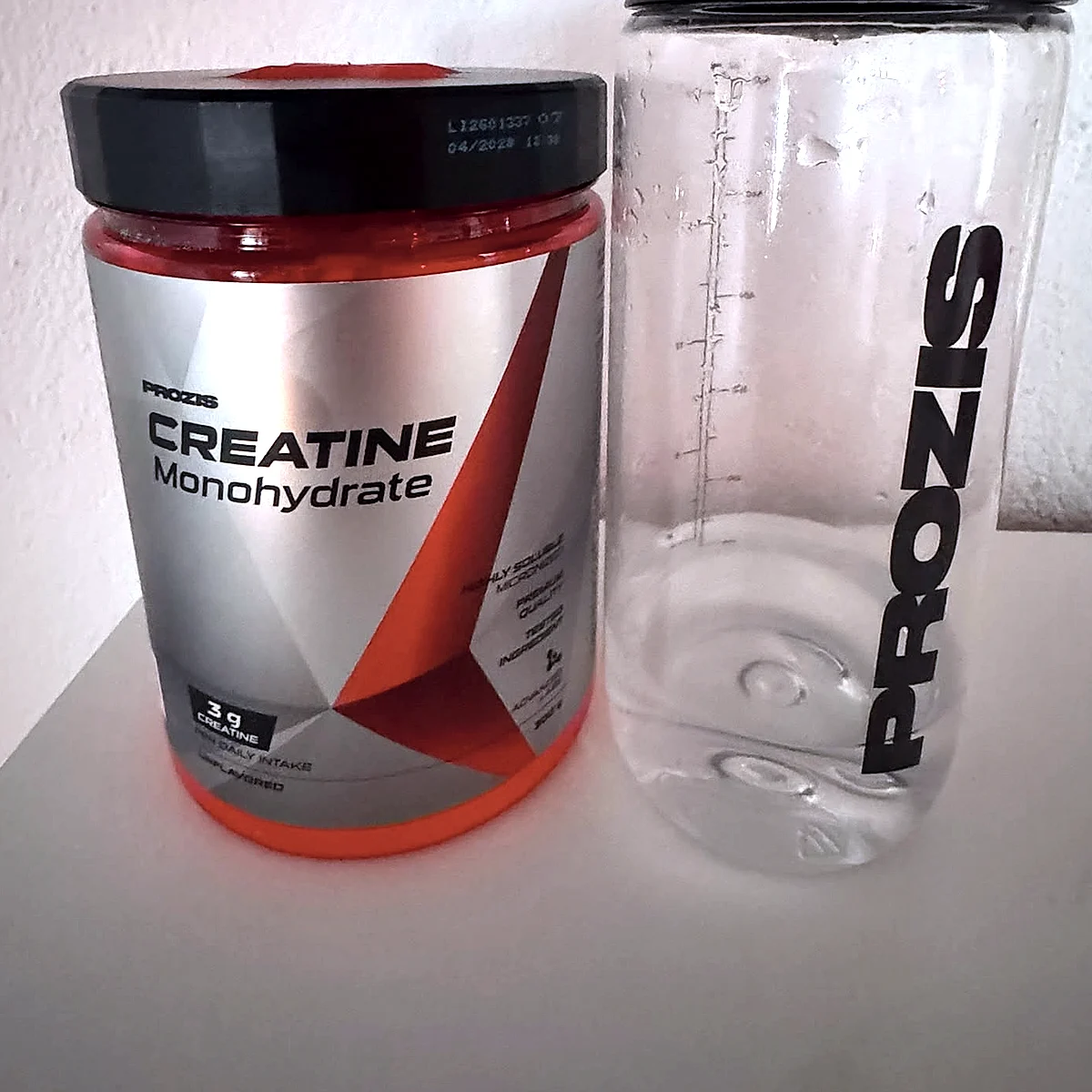 Frontal del envase de Prozis Monohidrato de Creatina 300 g junto al agitador