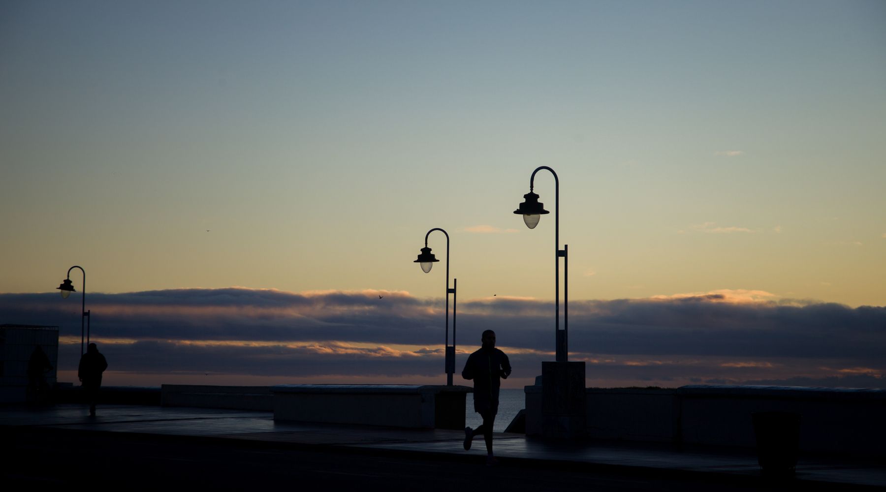 Corredor en silueta al atardecer en un paseo marítimo — imagen ilustrativa de una quedada de running junto al mar en Almería