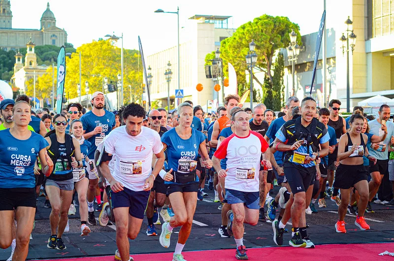 Corredores de la Cursa de la Mercè con el Palau Nacional de Montjuïc al fondo