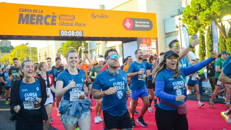 Ambiente festivo en la Cursa de la Mercè - corredores cruzando el arco oficial con camisetas oficiales
