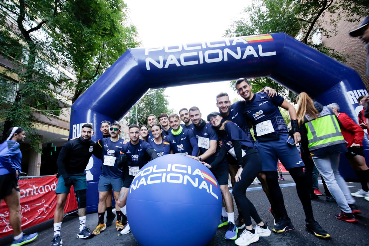 Grupo de corredores posando bajo el arco de salida de la Policía Nacional en la Ruta 091 de Madrid