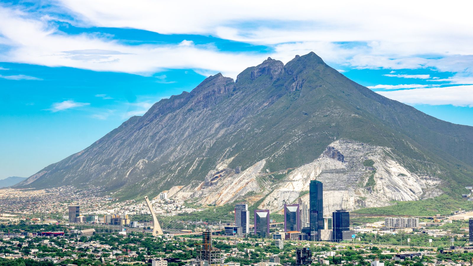 Skyline de Monterrey con el Cerro de la Silla al fondo bajo cielo azul