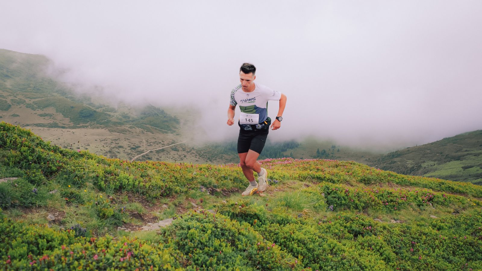 Corredor de trail en montaña verde con niebla, ambiente del maratón de montaña Zegama-Aizkorri