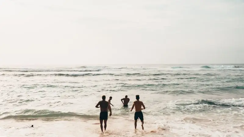 Corredores corriendo junto al mar en la playa durante el dia