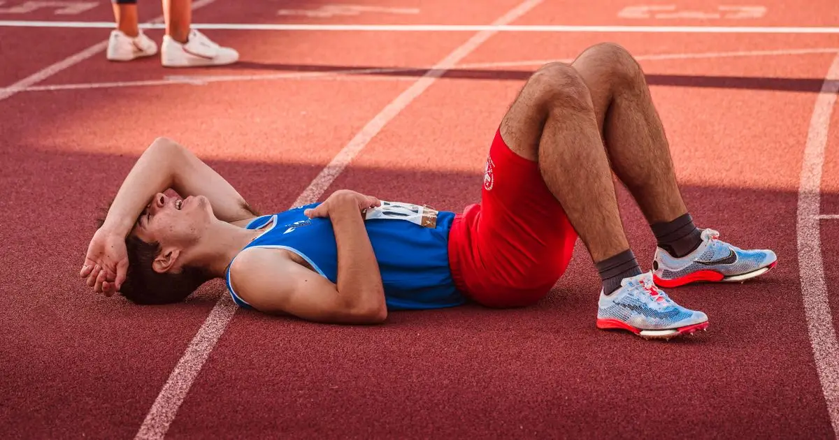 Corredor agotado descansando tras un entrenamiento intenso - sobreentrenamiento running