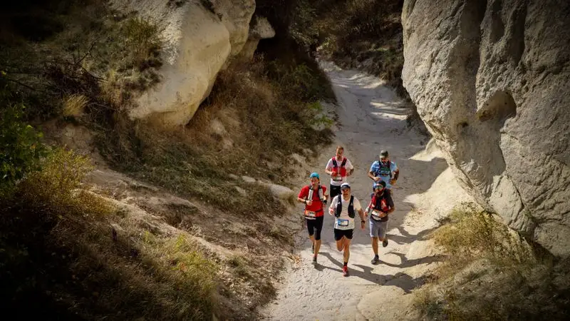 Trail runners corriendo por un sendero de monta&ntilde;a entre formaciones rocosas