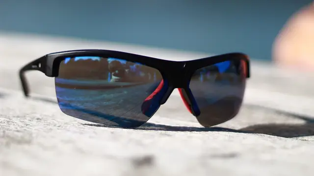 Imagen ambiental: gafas de sol deportivas apoyadas sobre una piedra al aire libre
