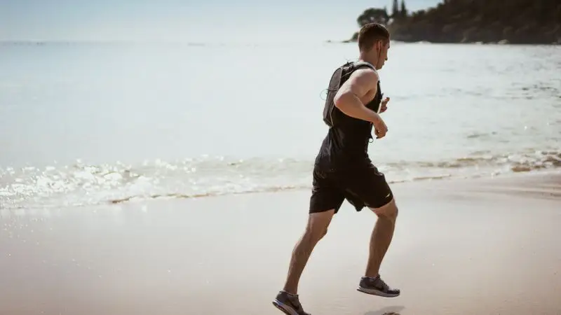 Hombre corriendo por la orilla del mar con olas rompiendo en la playa