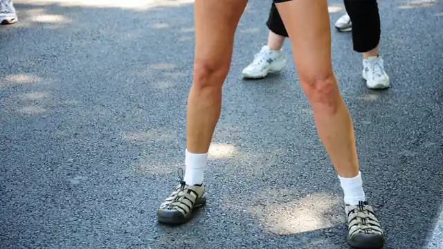 Piernas y zapatillas de dos corredores vistas desde atr&aacute;s sobre asfalto