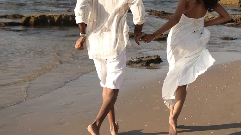 Pareja corriendo juntos por una playa de arena al atardecer