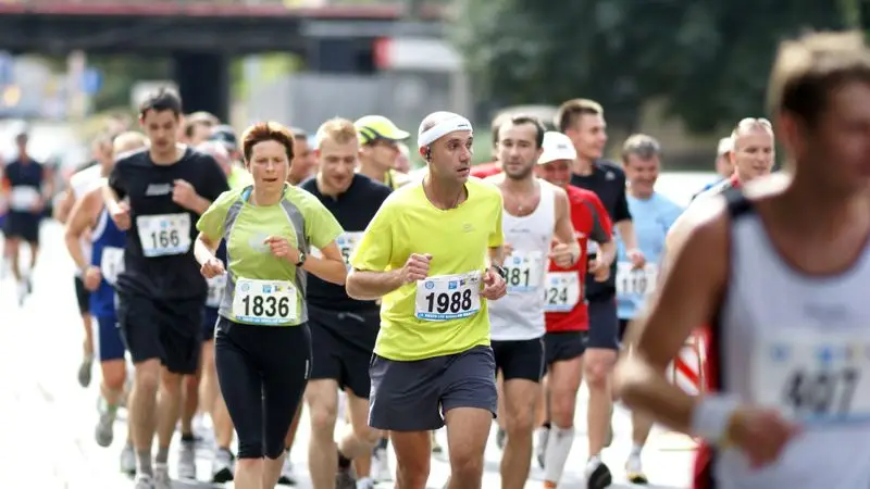 Grupo de corredores adultos con dorsales compitiendo en una carrera popular urbana