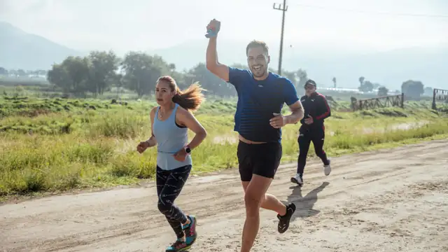 Grupo de tres corredores entrenando juntos por un camino de tierra en el campo