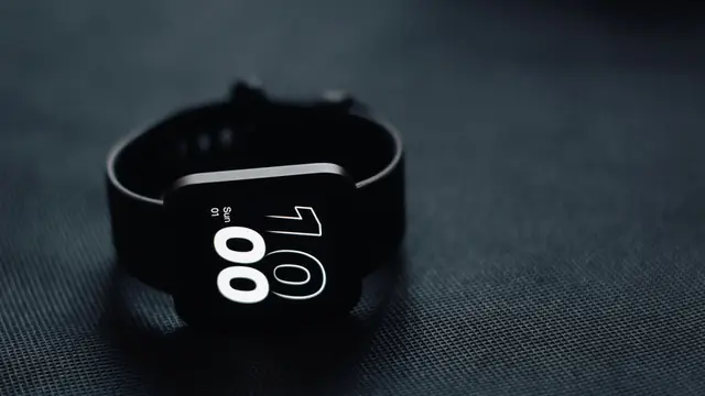 Imagen ambiental: pulsera de actividad con pantalla encendida sobre una superficie oscura; no corresponde a ning&uacute;n modelo analizado