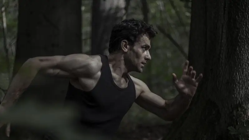 Hombre corriendo intensamente por un bosque denso durante un entrenamiento de trail