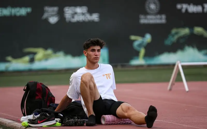 Atleta usando rodillo de masaje en las piernas para recuperaci&oacute;n muscular despu&eacute;s de correr