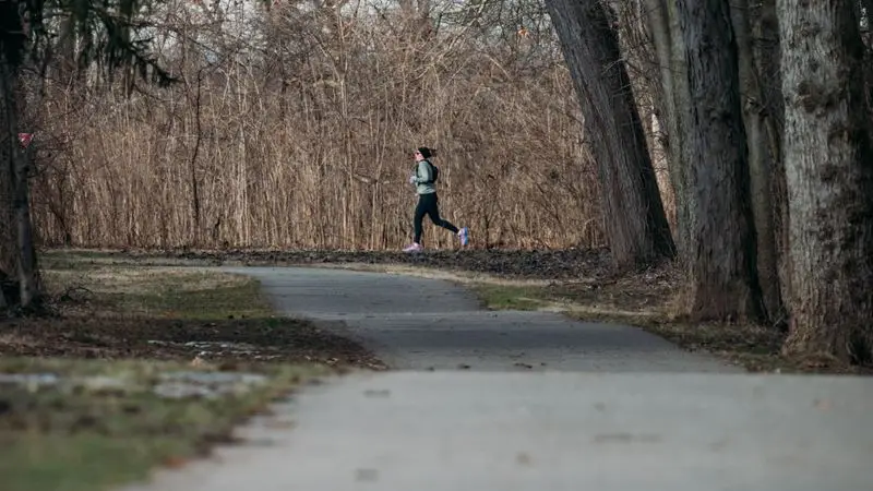 Runner principiante corriendo por un camino arbolado en un parque