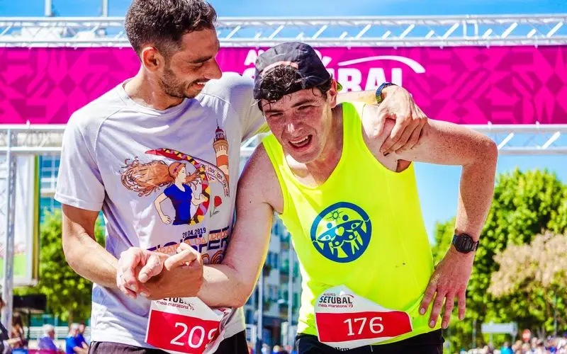 Corredor agotado recibiendo ayuda de otro runner durante entrenamiento