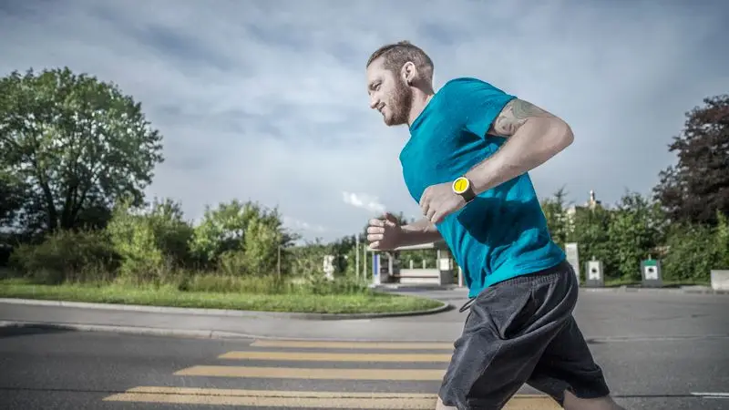Runner adulto corriendo con buena postura y técnica por una carretera