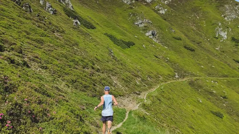 Trail runner corriendo por un paisaje verde de montana
