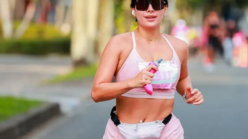 Mujer haciendo jogging por un parque urbano con ropa deportiva colorida