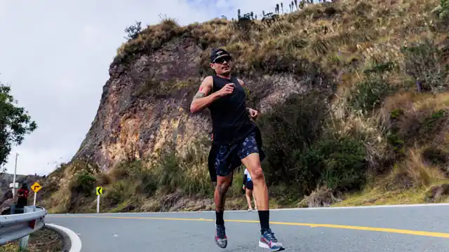 Corredor entrenando por una carretera al pie de una ladera