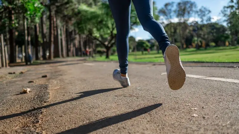 Corredor haciendo un rodaje largo por un parque en otoño con luz dorada