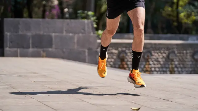 Piernas de un corredor en movimiento sobre el pavimento de un paseo urbano