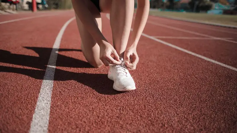 Runner en pista de atletismo entrenando intervalos para sub-1:45 en media maratón