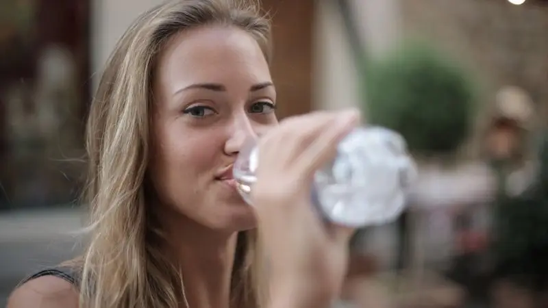 Runner hidratándose con botella de agua durante entrenamiento