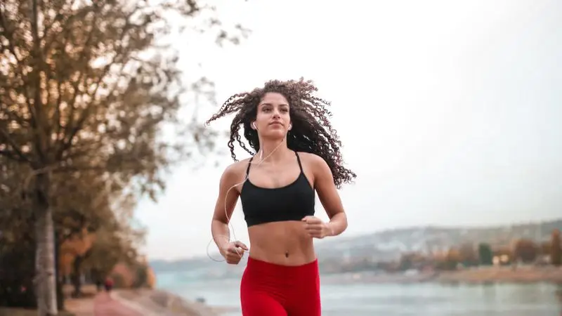 Mujer corriendo al aire libre con ropa deportiva en entorno urbano