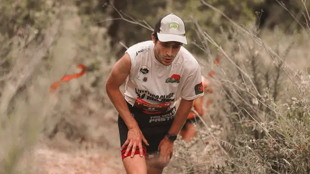 Corredor con gorra t&eacute;cnica blanca avanzando por un sendero seco