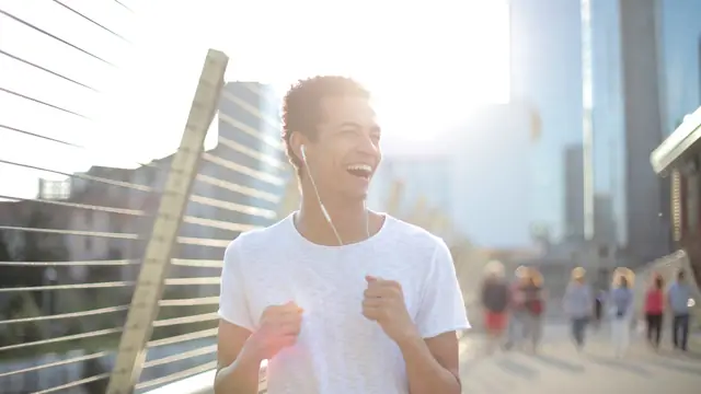 Corredor con auriculares de cable corriendo por un paseo urbano a primera hora