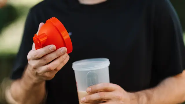 Persona sosteniendo un vaso mezclador con un batido de prote&iacute;nas tras el entrenamiento