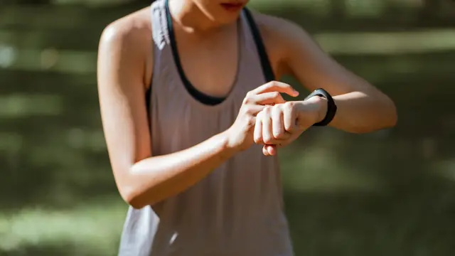 Imagen ambiental: corredora consultando su reloj deportivo en un parque; no corresponde al modelo analizado