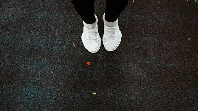 Vista cenital de unas zapatillas de running blancas apoyadas sobre el asfalto