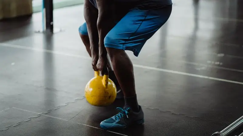 Atleta agarrando kettlebell amarilla en el gimnasio