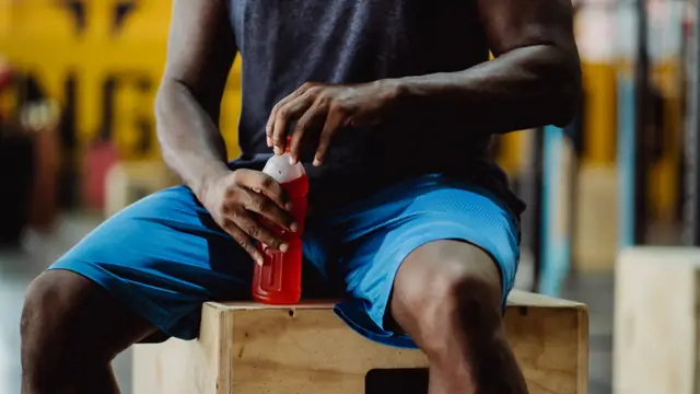Imagen ambiental: deportista sosteniendo una bebida energ&eacute;tica durante una pausa del entrenamiento