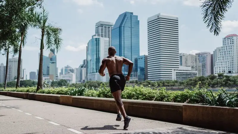 Runner corriendo por un camino urbano junto a un parque