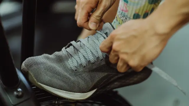 Manos at&aacute;ndose los cordones de una zapatilla de running antes de entrenar
