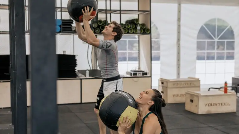 Atleta realizando ejercicio con bal&oacute;n medicinal en box de CrossFit