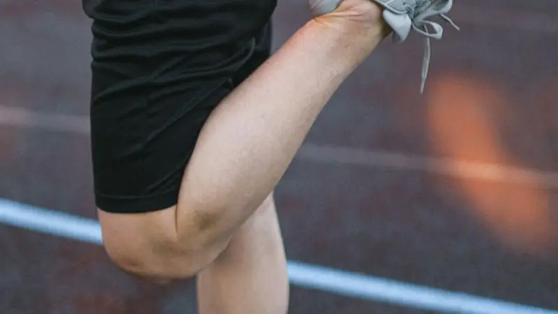 Deportista estirando las piernas en una pista de atletismo antes del entrenamiento