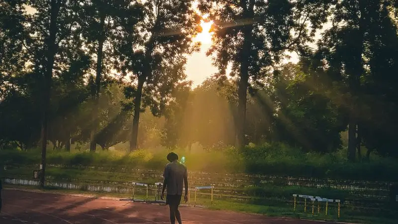 Hombre caminando por una pista de atletismo al amanecer