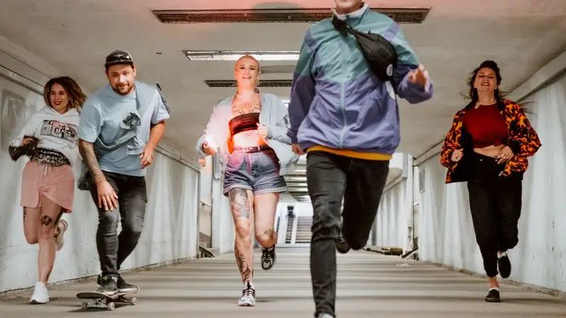 Group of young people running together through an urban tunnel