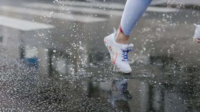 Zapatilla de running pisando un charco y levantando salpicaduras de agua